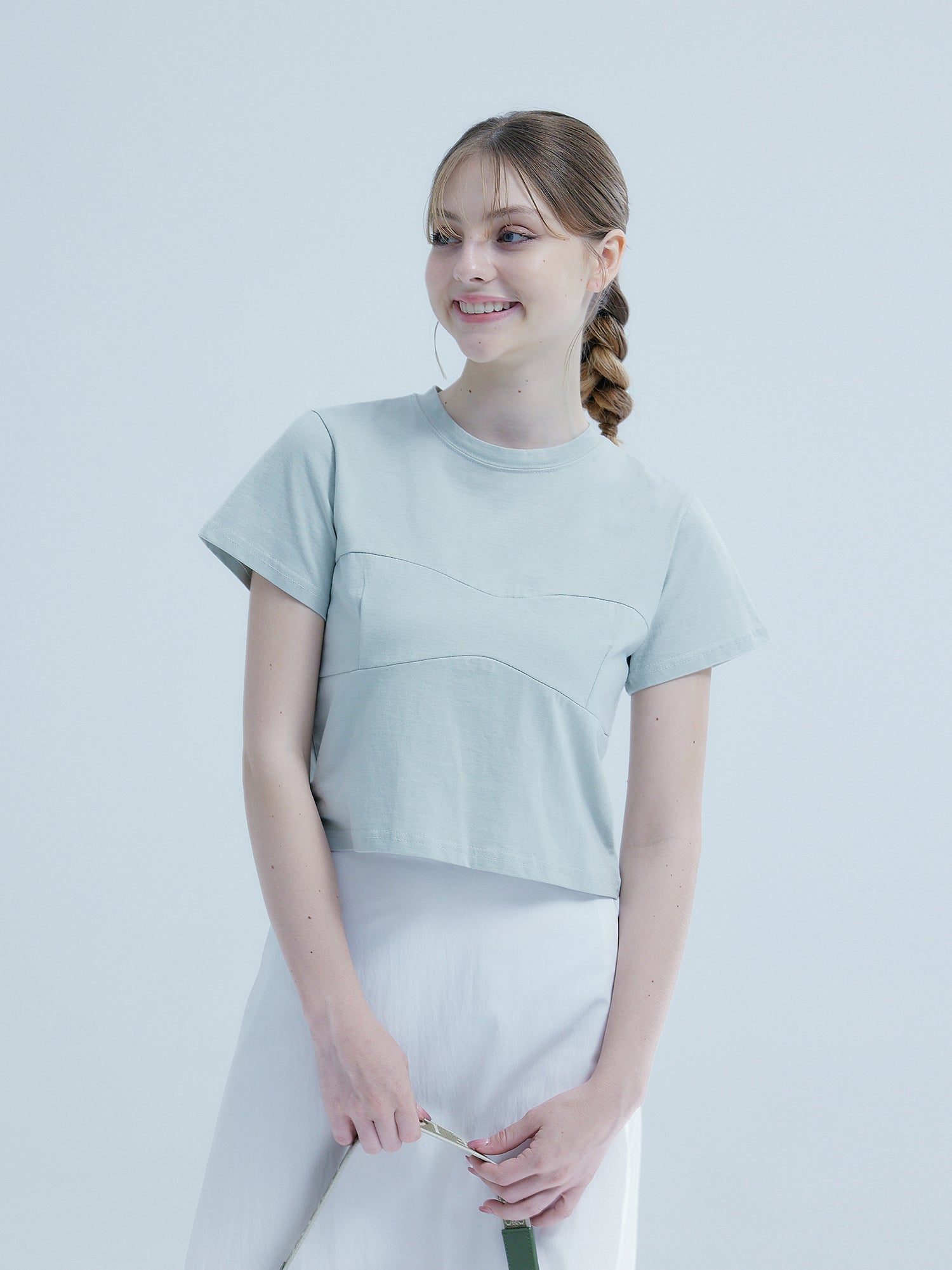 The model, casting a sideways glance, exhibits the front details of her South Korea fashion-inspired chest seam top, highlighting its unique design.