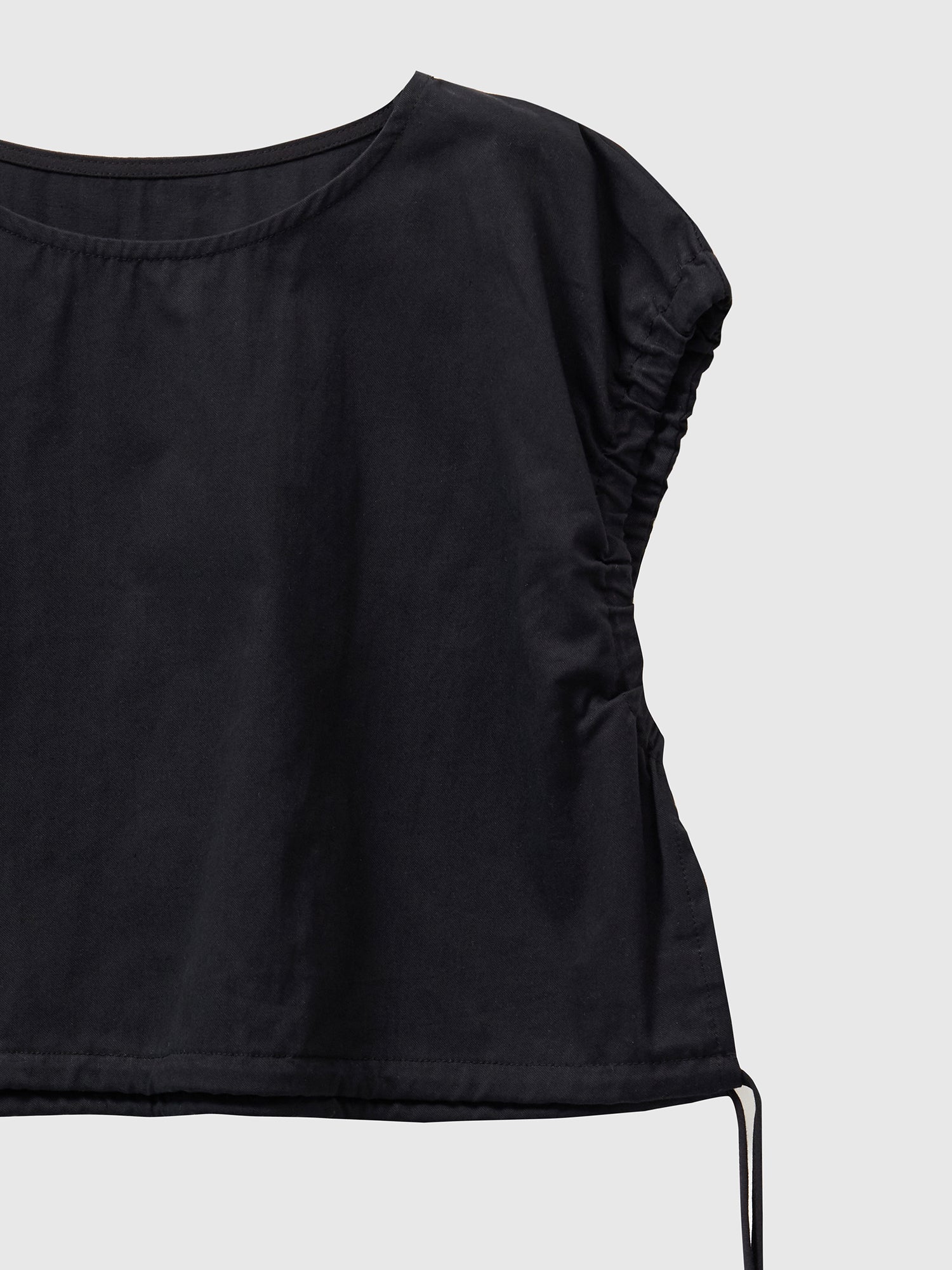 Zoomed-in shot of black elastic waist crop top highlighting the elastic detail design on the sleeve.