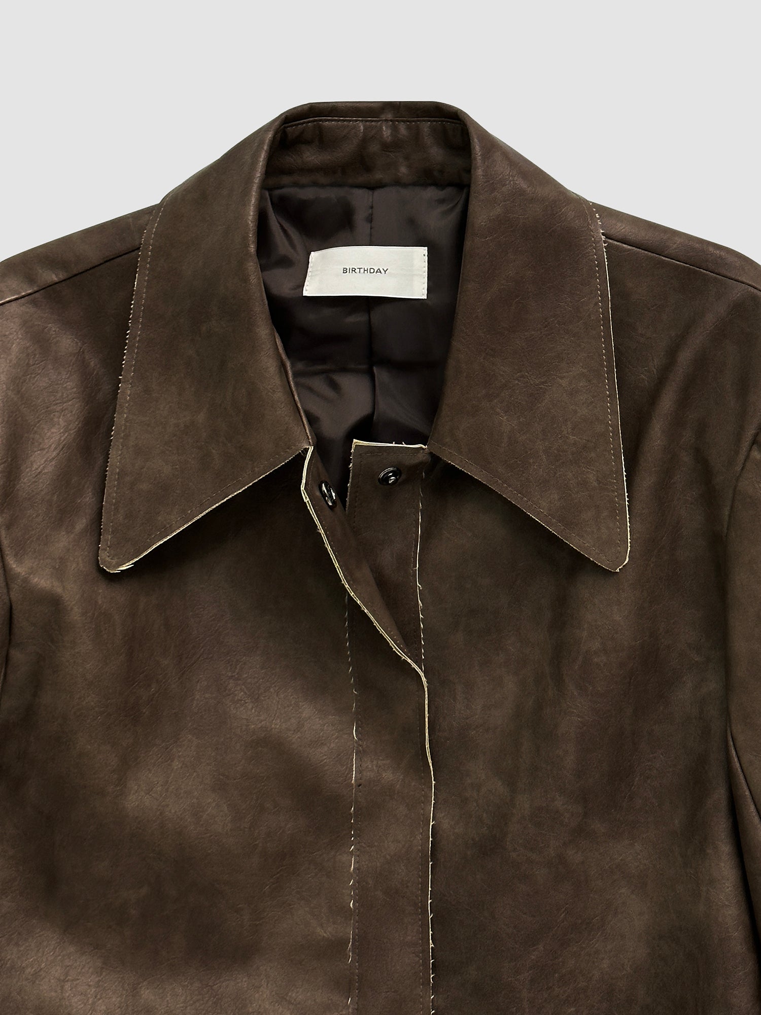 A close-up view of the cropped leather jacket showing the intricate details of the collars and fabric of the jacket.