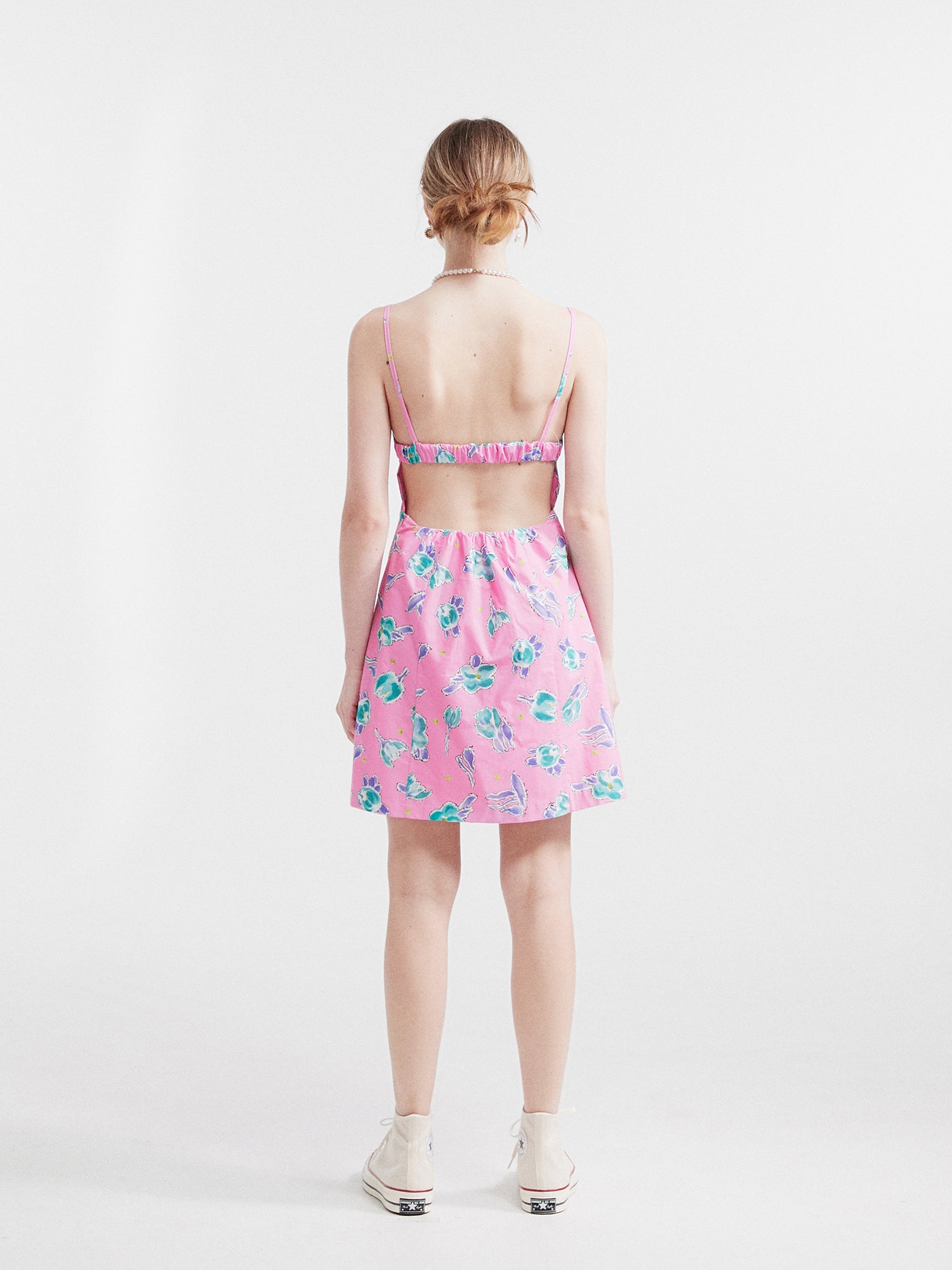 A model standing backside wearing the floral mini dress showcasing the back designs.