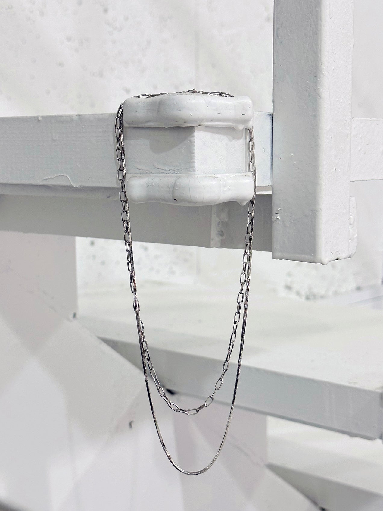 The Layered Paperclip Necklace is captured in a photo, gracefully hanging on the edge, showcasing its full length with elegance.