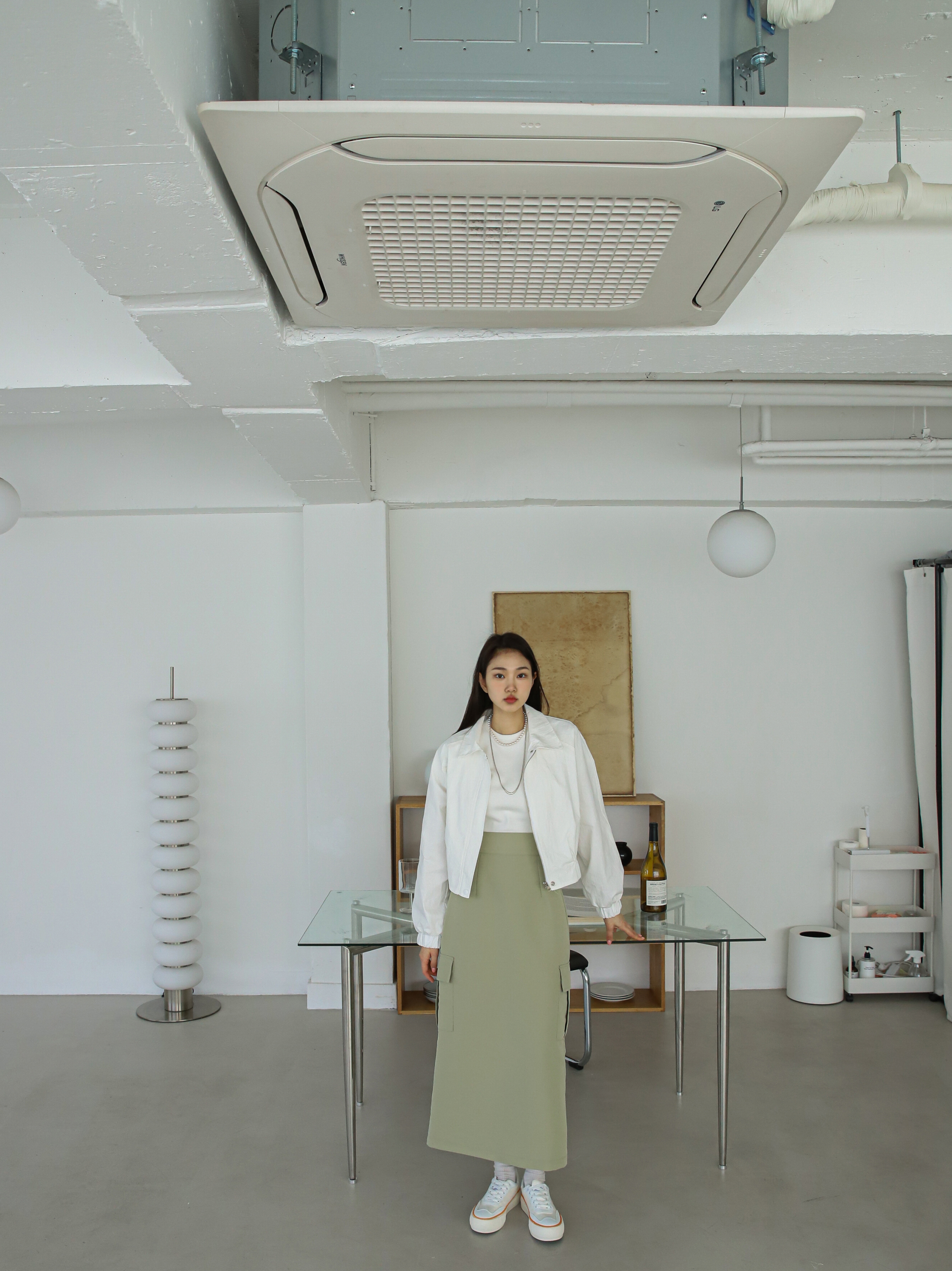 A model standing up wearing Ivory bomber jacket with midi pocketed skirt.