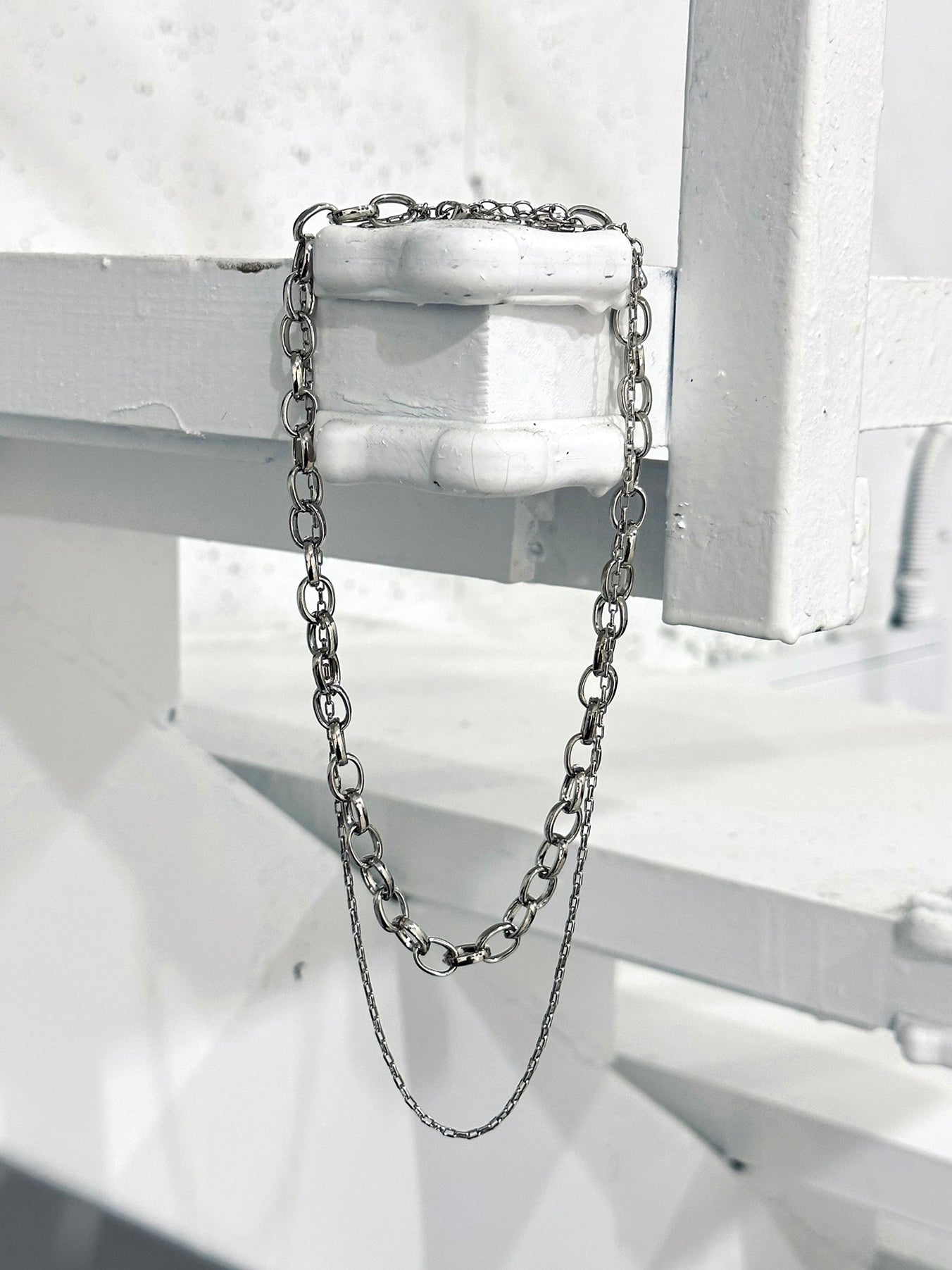 Elegantly displayed, a photograph captures the Layered Chain Necklace gracefully hanging on the edge, revealing its full length with captivating elegance.