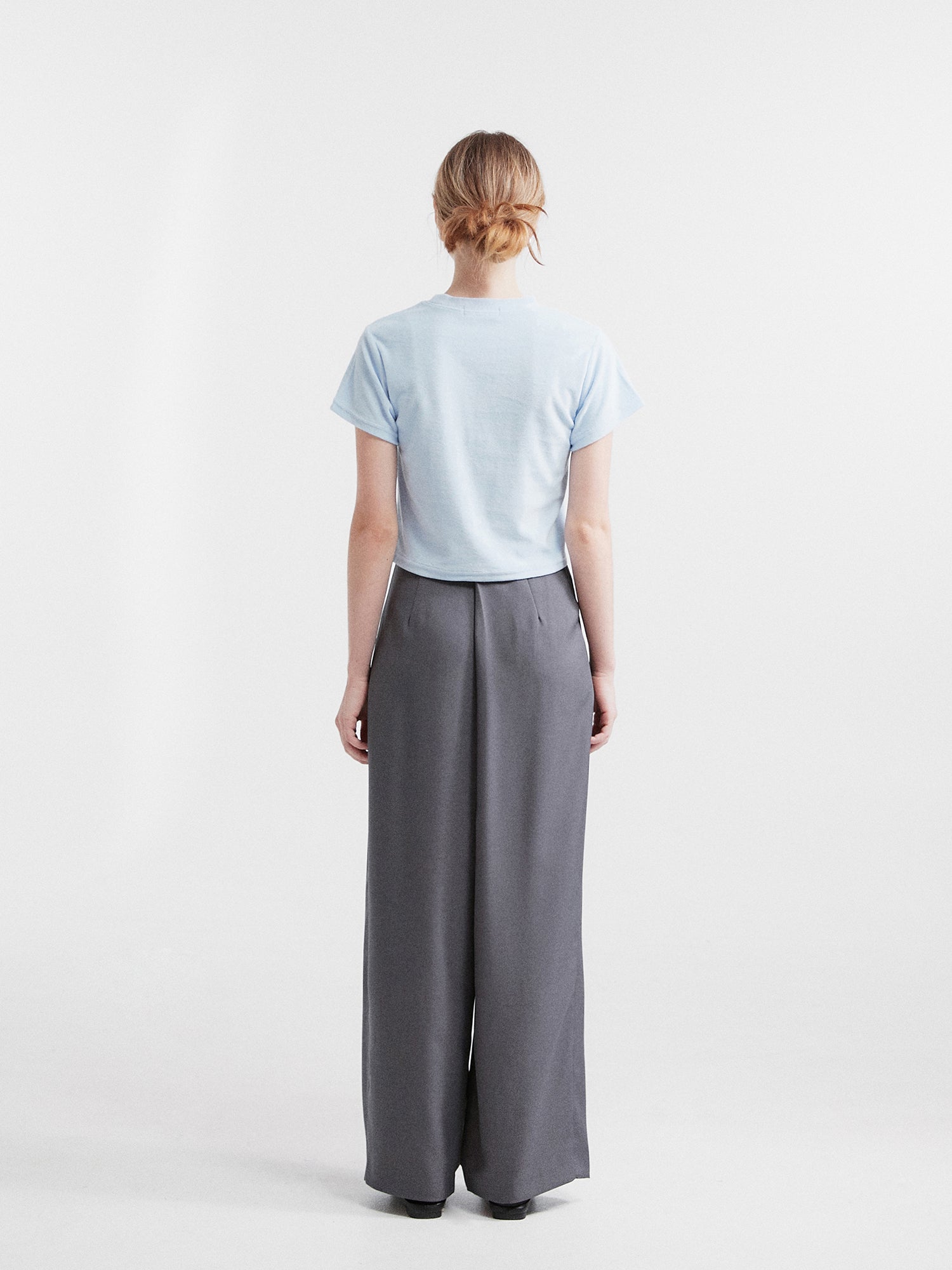 It captures the back view of the model wearing the side-belted trousers, highlighting the stylish backside of the garment.