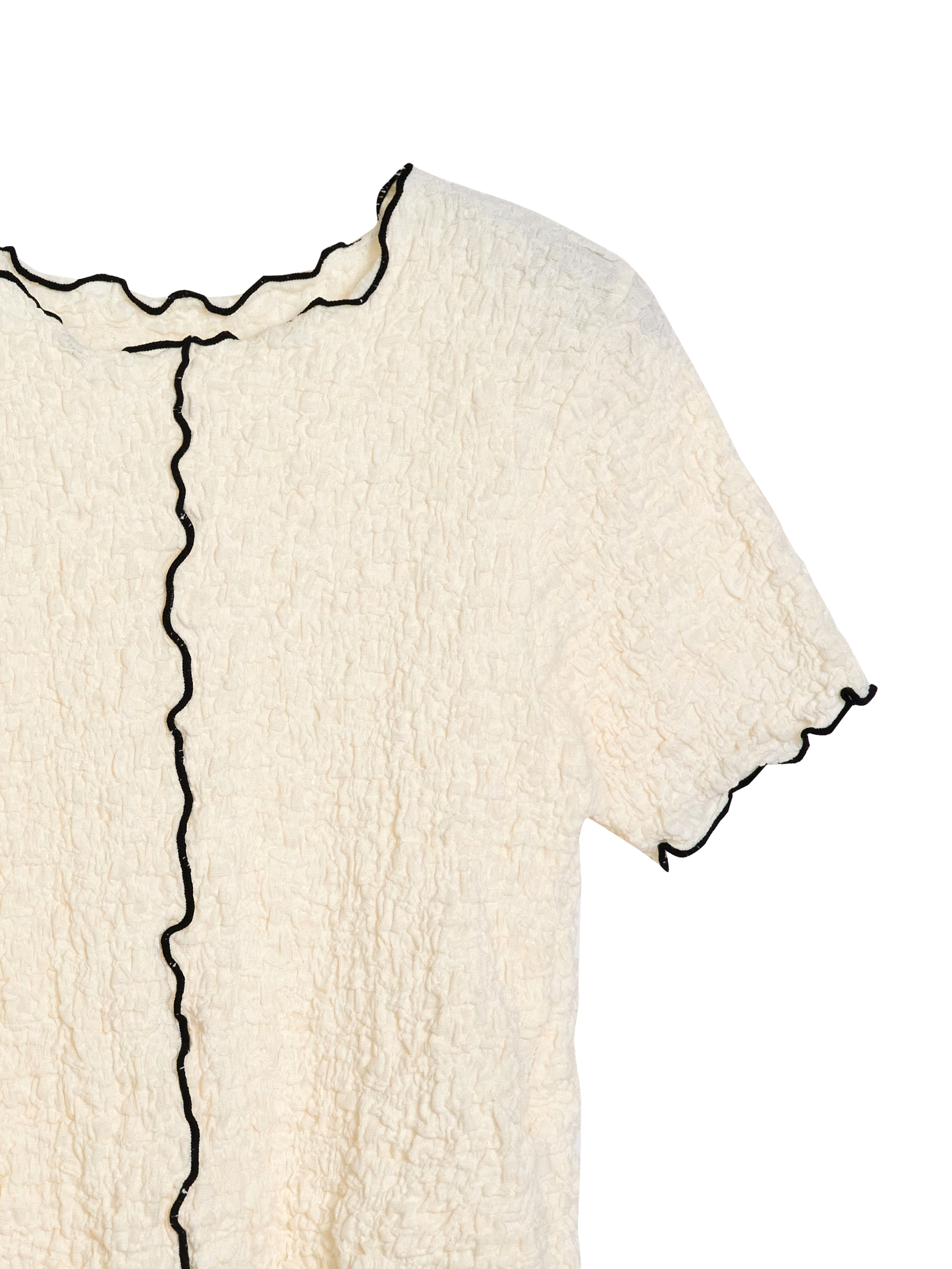 Up-close detailed look of a cream textured top showcasing the contrast lining detail of the design.