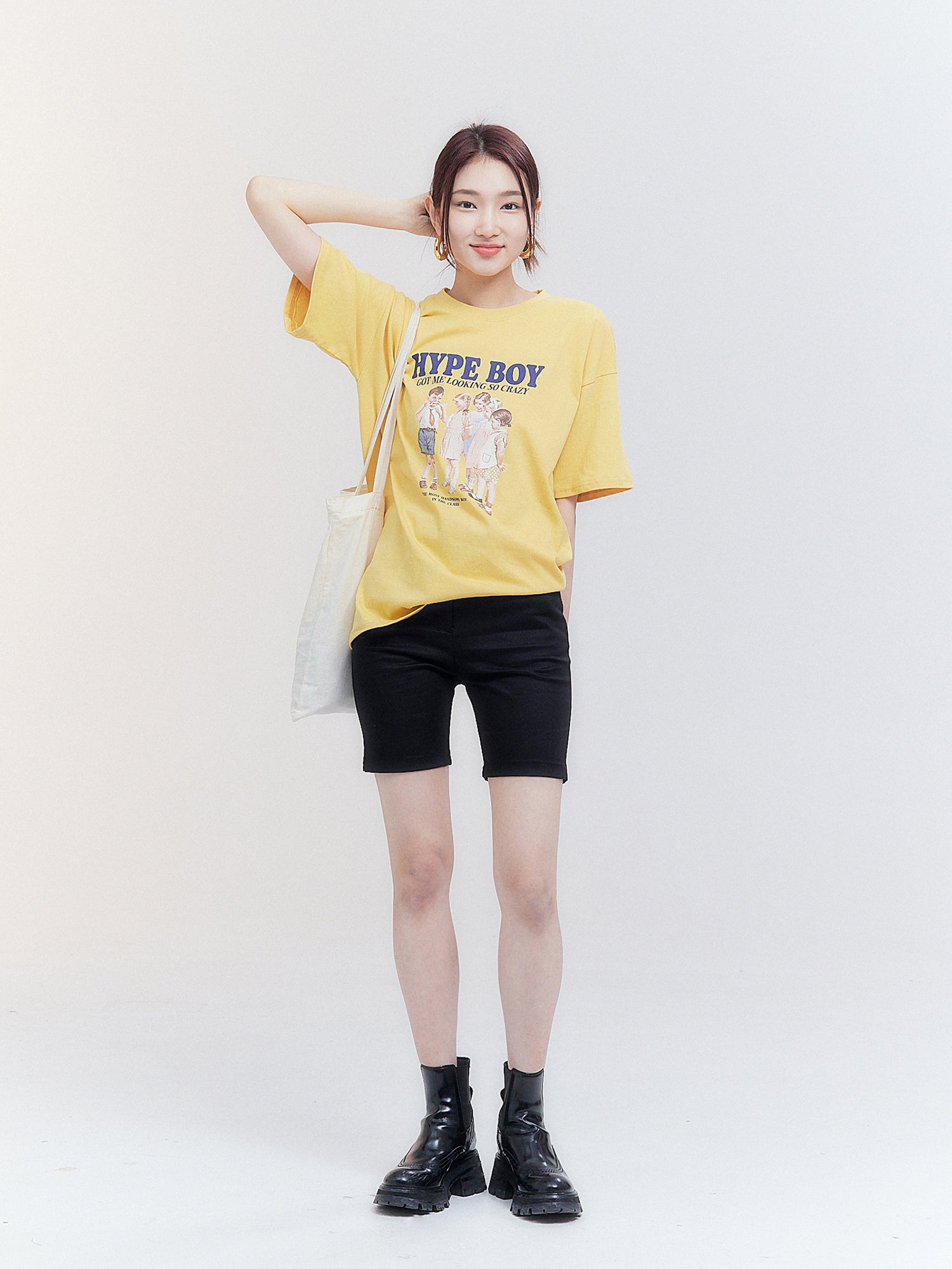 A front-facing shot showcases the model in a South Korea fashion inspired yellow Hype Boy t-shirt, accentuating the shirt's full extent and stylish appeal.