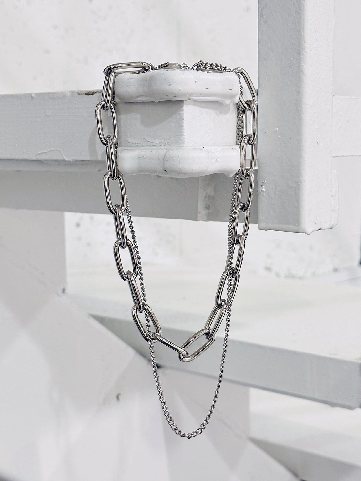 The Bold Chain Necklace is captured in a photo, gracefully hanging on the edge, showcasing its full length with elegance.