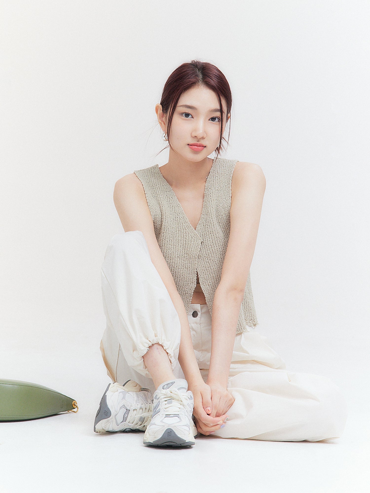 The model, embodying Korean street fashion, strikes a seated pose on the ground while wearing the open-front tank top, exuding confidence and style.