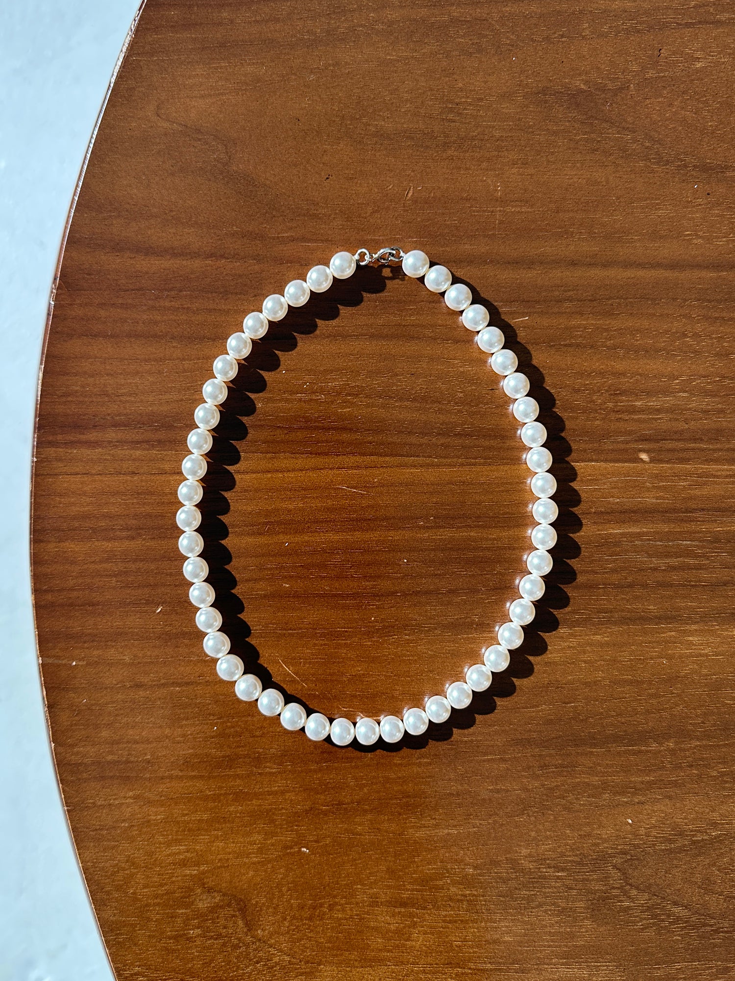 A picture of a pearl necklace delicately arranged on the table.