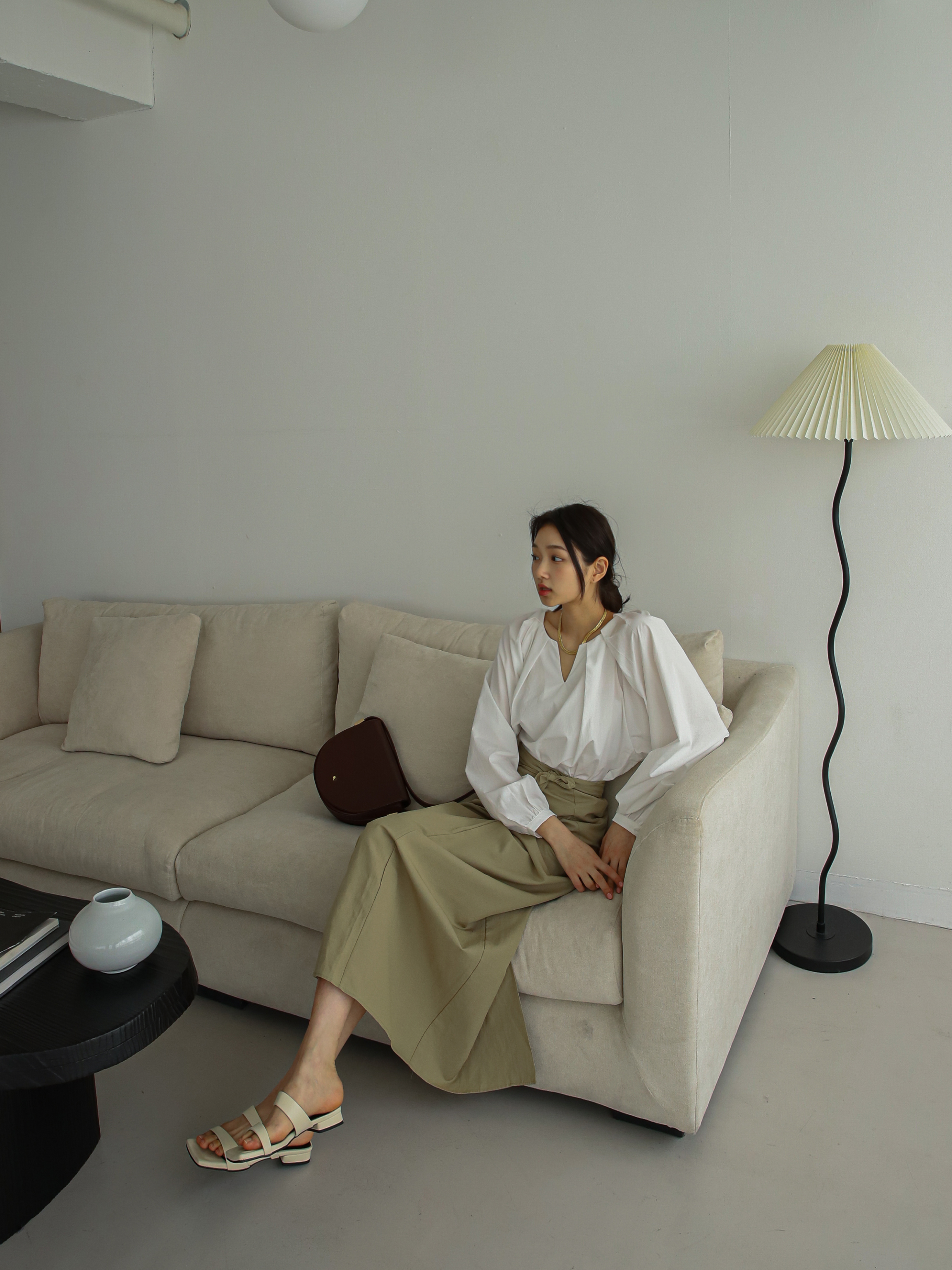 Seated gracefully, the model showcases the elegant design of the raglan sleeve blouse, emphasizing its sophisticated allure.