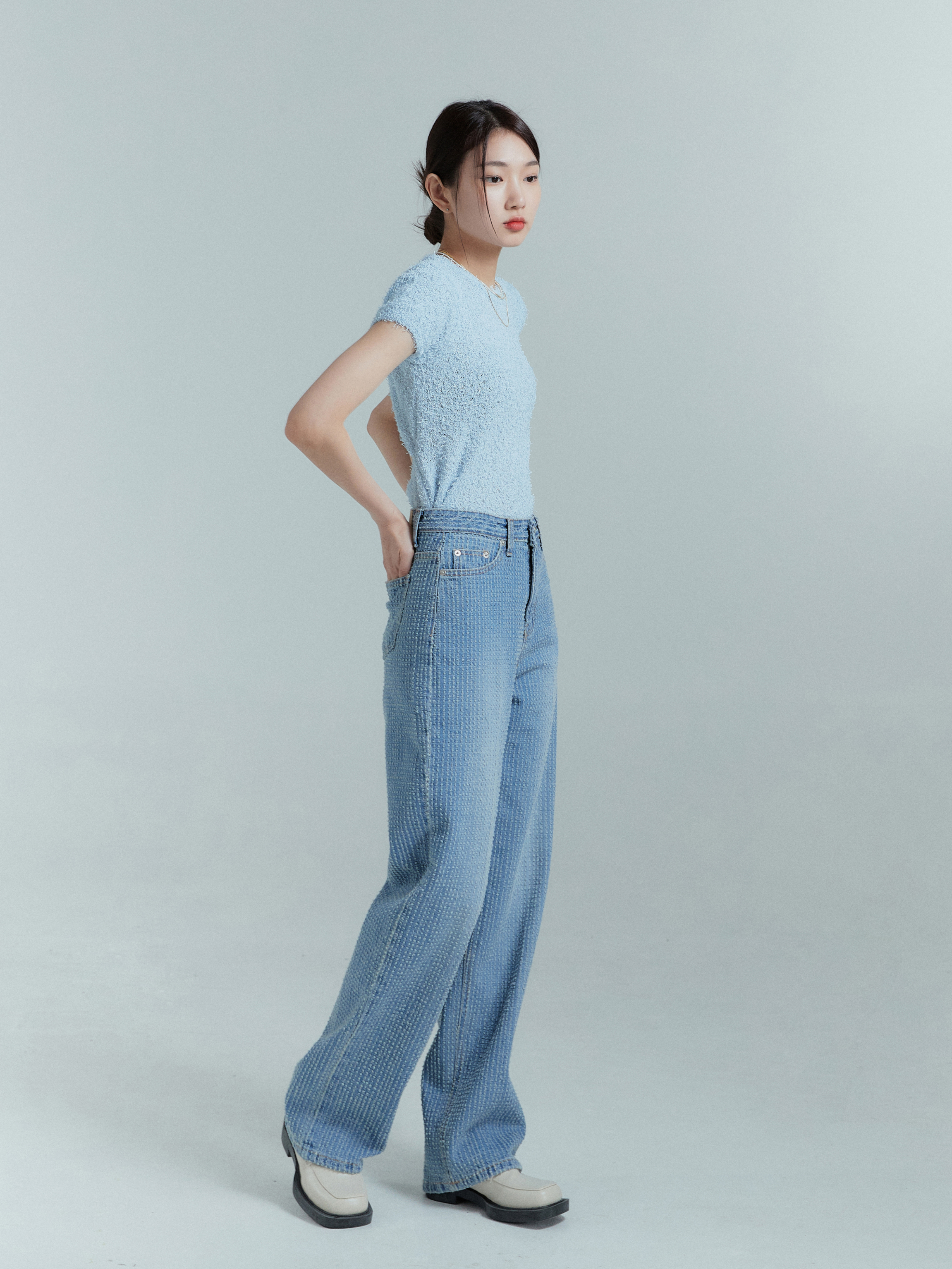 From a side angle, the model confidently flaunts the medium-washed striped jeans, highlighting their stylish side profile.