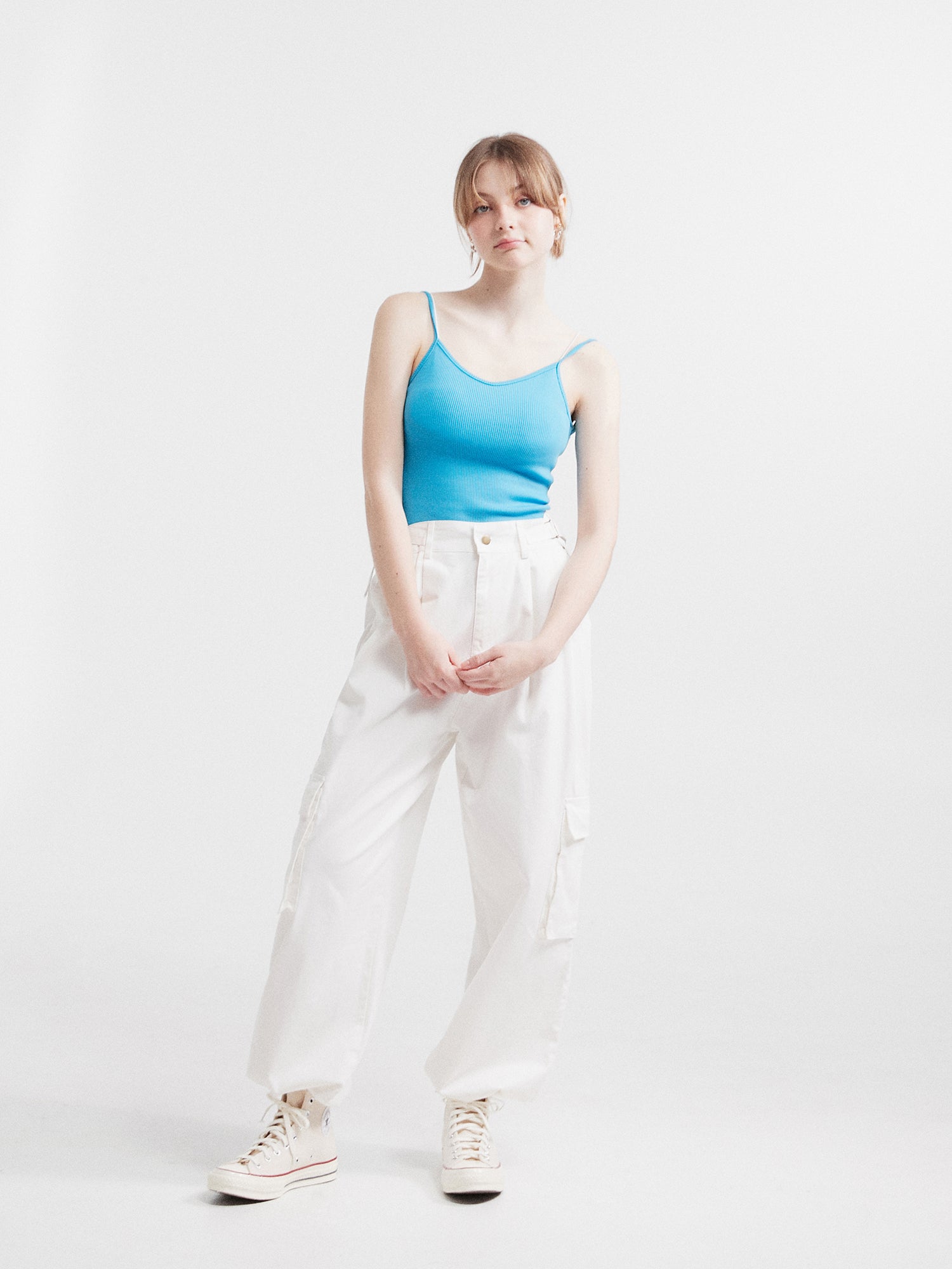 Full-shot of a model wearing the blue tank top with white cargo pants.