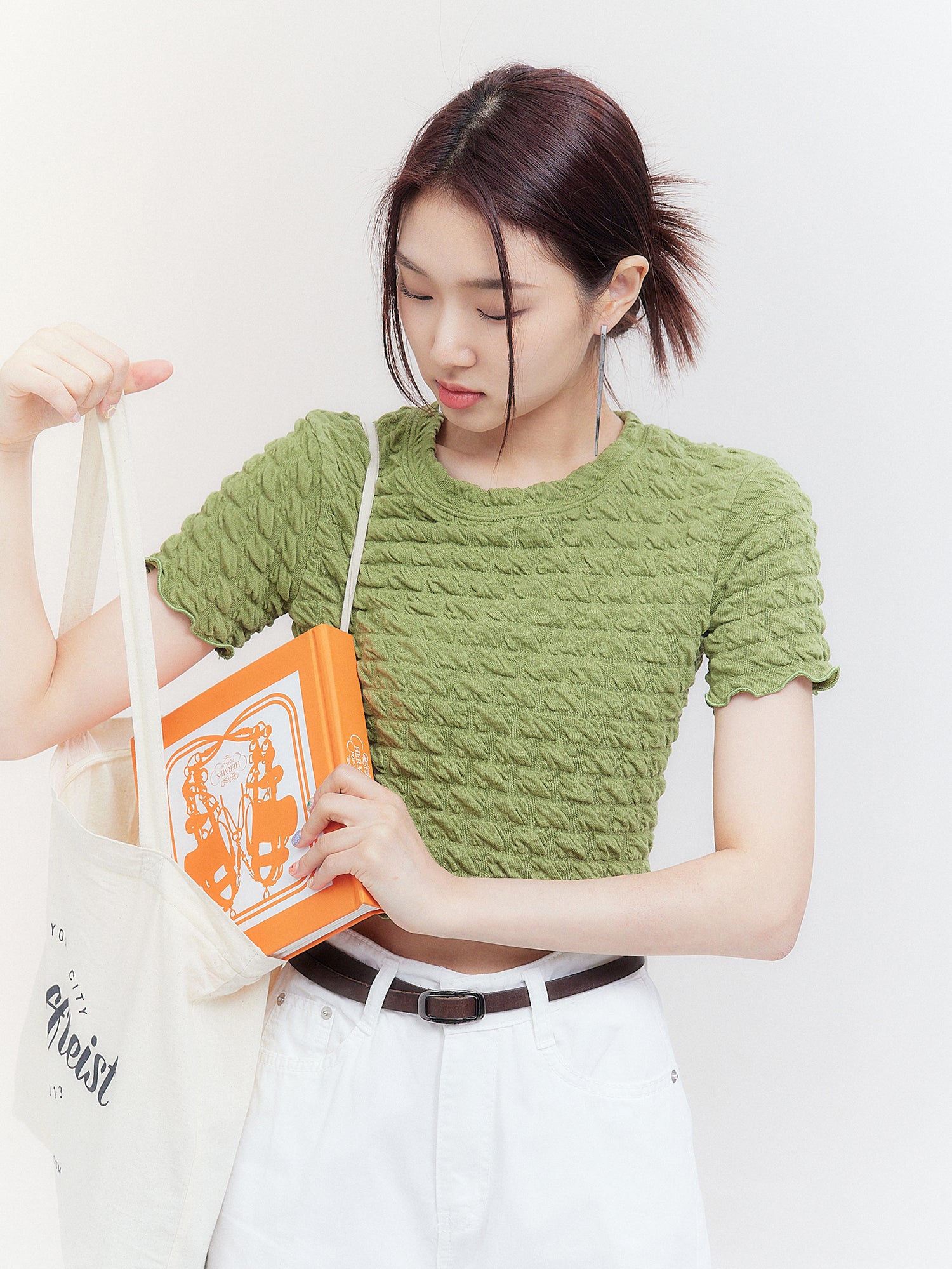 The model is sliding a book into her bag, effortlessly displaying her stylish waffle-textured top.