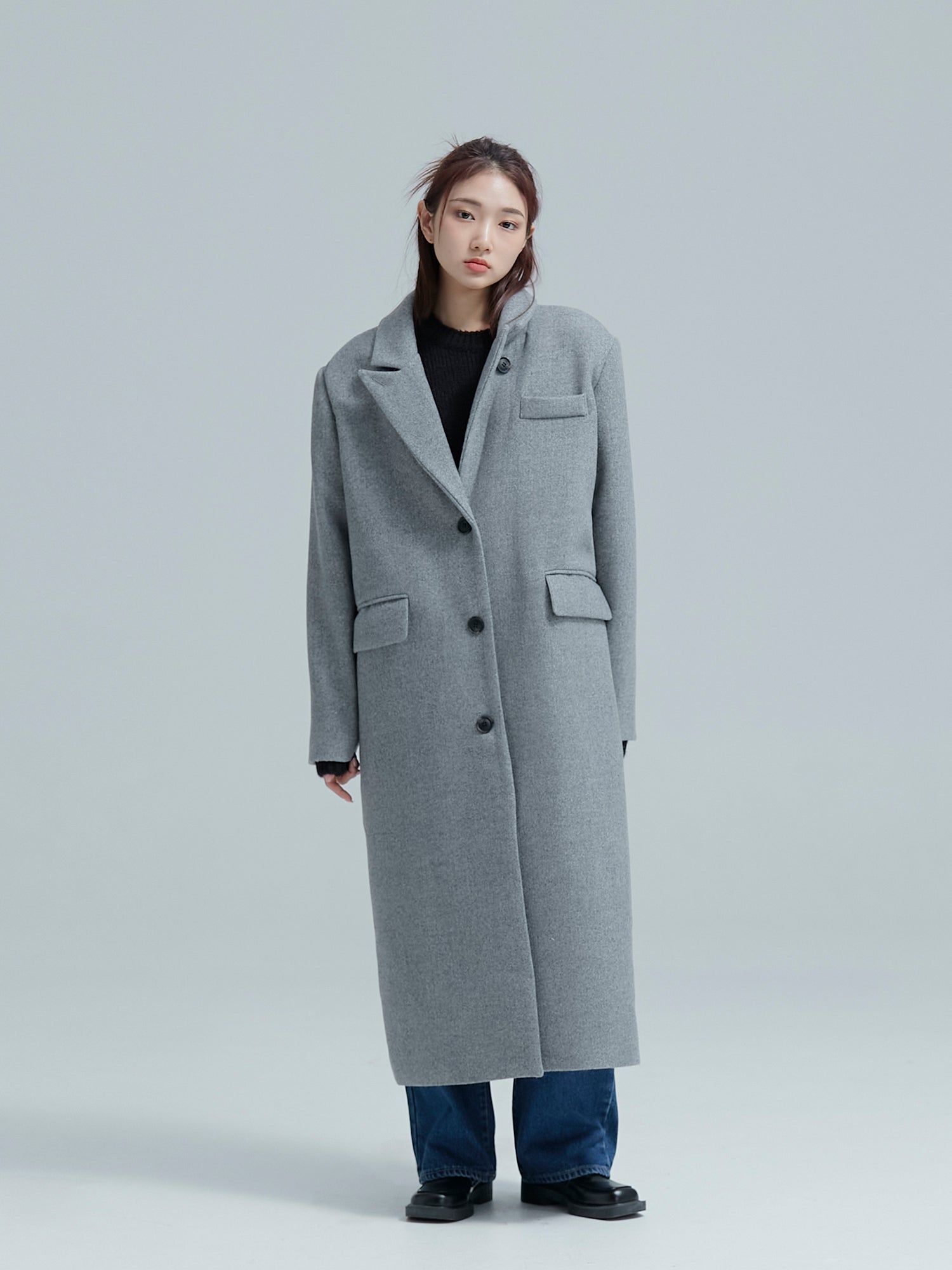 Full look of the model wearing the gray wool coat to showcase its full fitting of the coat with the button closed-up.